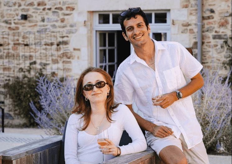Smiling attendees enjoy a corporate offsite with wine outdoors at a charming historic stone venue.