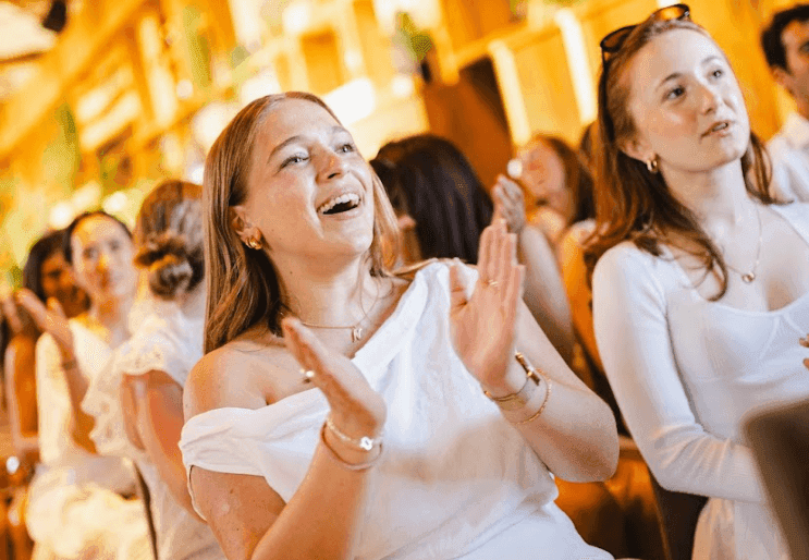 Attendees clap and smile during an engaging corporate event or team building activity.