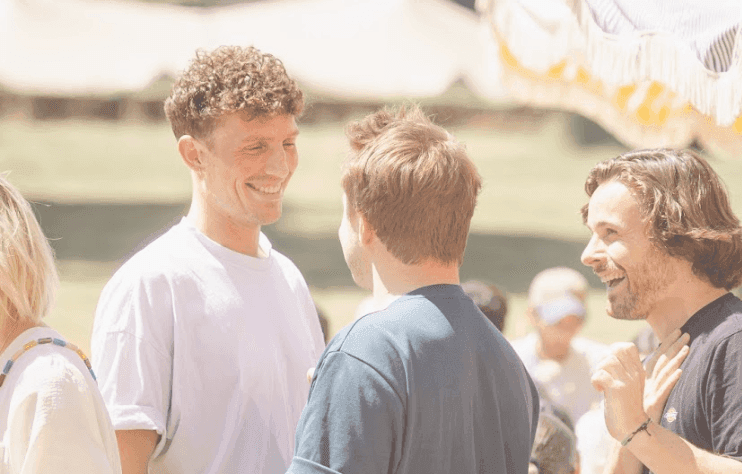 Three smiling colleagues engaging in conversation outdoors during a corporate team building activity.