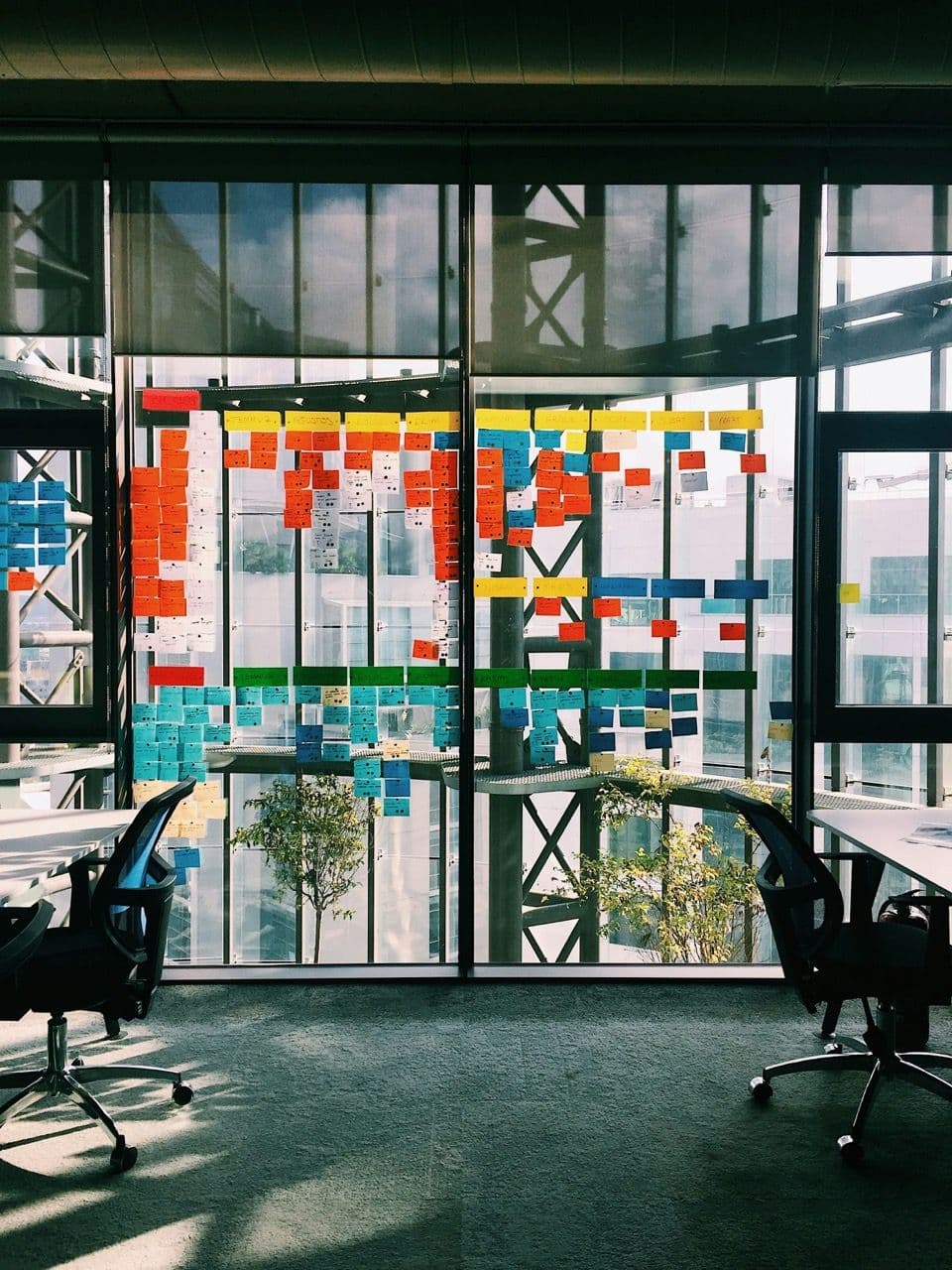 Modern meeting room with large windows covered in colorful sticky notes for a collaborative workshop.