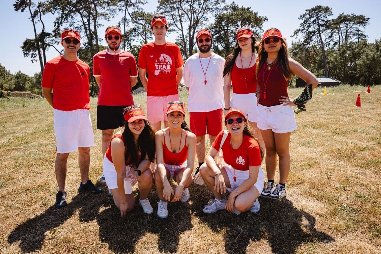 A group of colleagues in red and white outfits enjoying an outdoor team building activity.