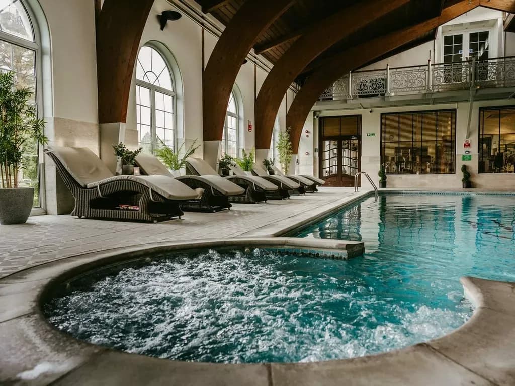 Indoor swimming pool and jacuzzi with lounge chairs, perfect for a corporate retreat venue.