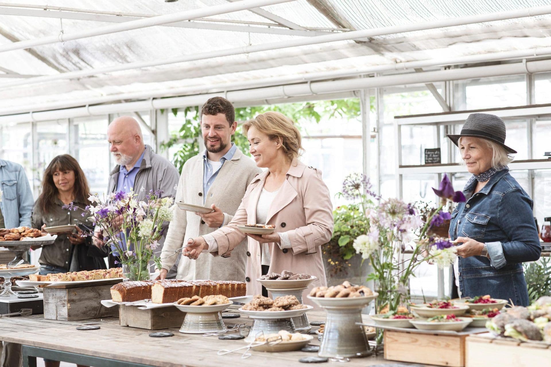 Guests serve themselves from a buffet table with cakes and cookies during a corporate seminar break.
