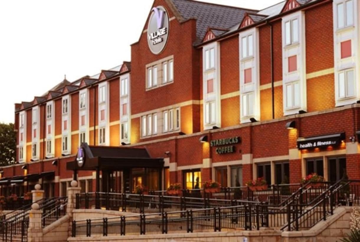 Exterior of Village Hotel Coventry, a red brick corporate event venue with a Starbucks and health club.