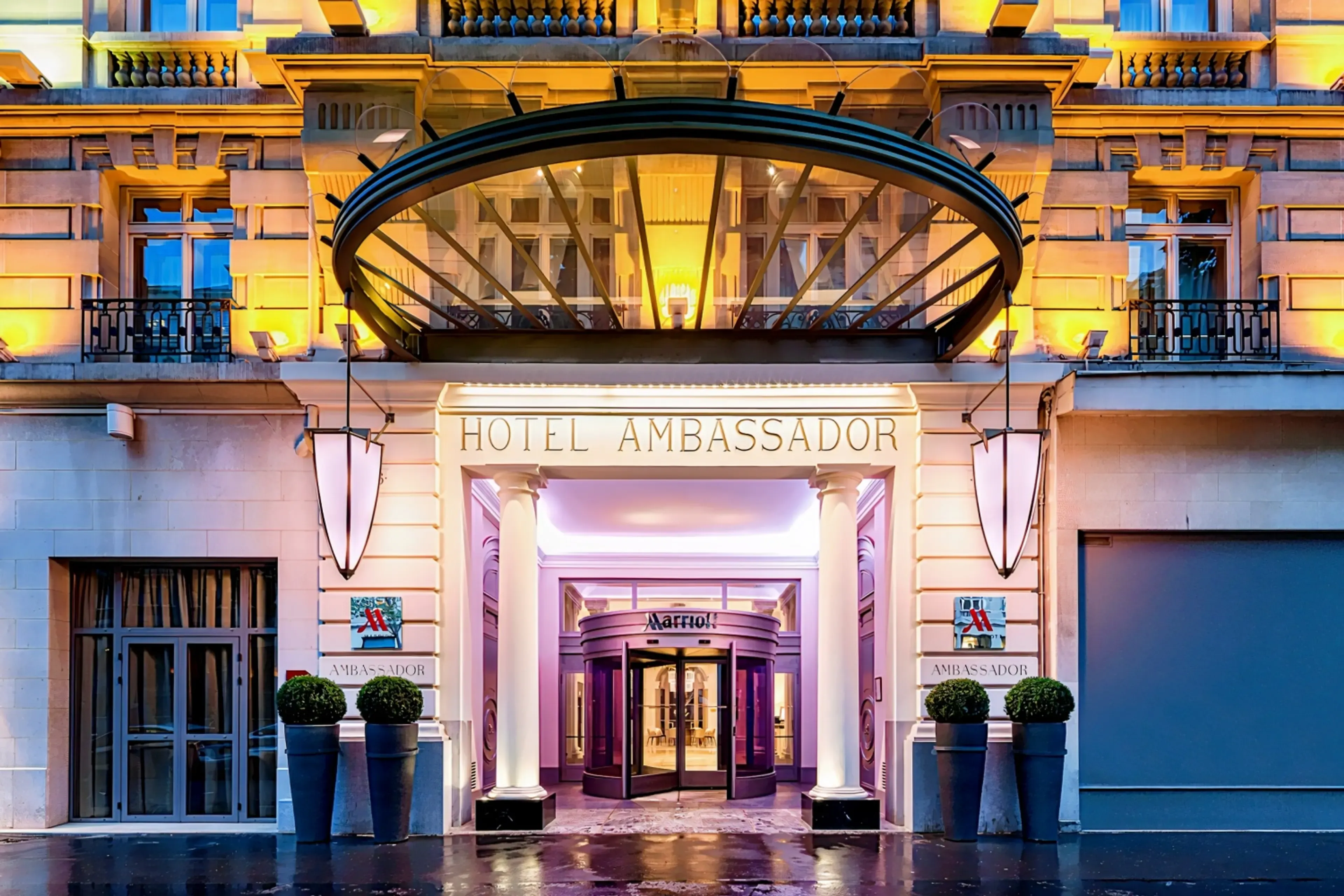 The illuminated entrance of the Hotel Ambassador Marriott, a grand corporate event venue in Paris.