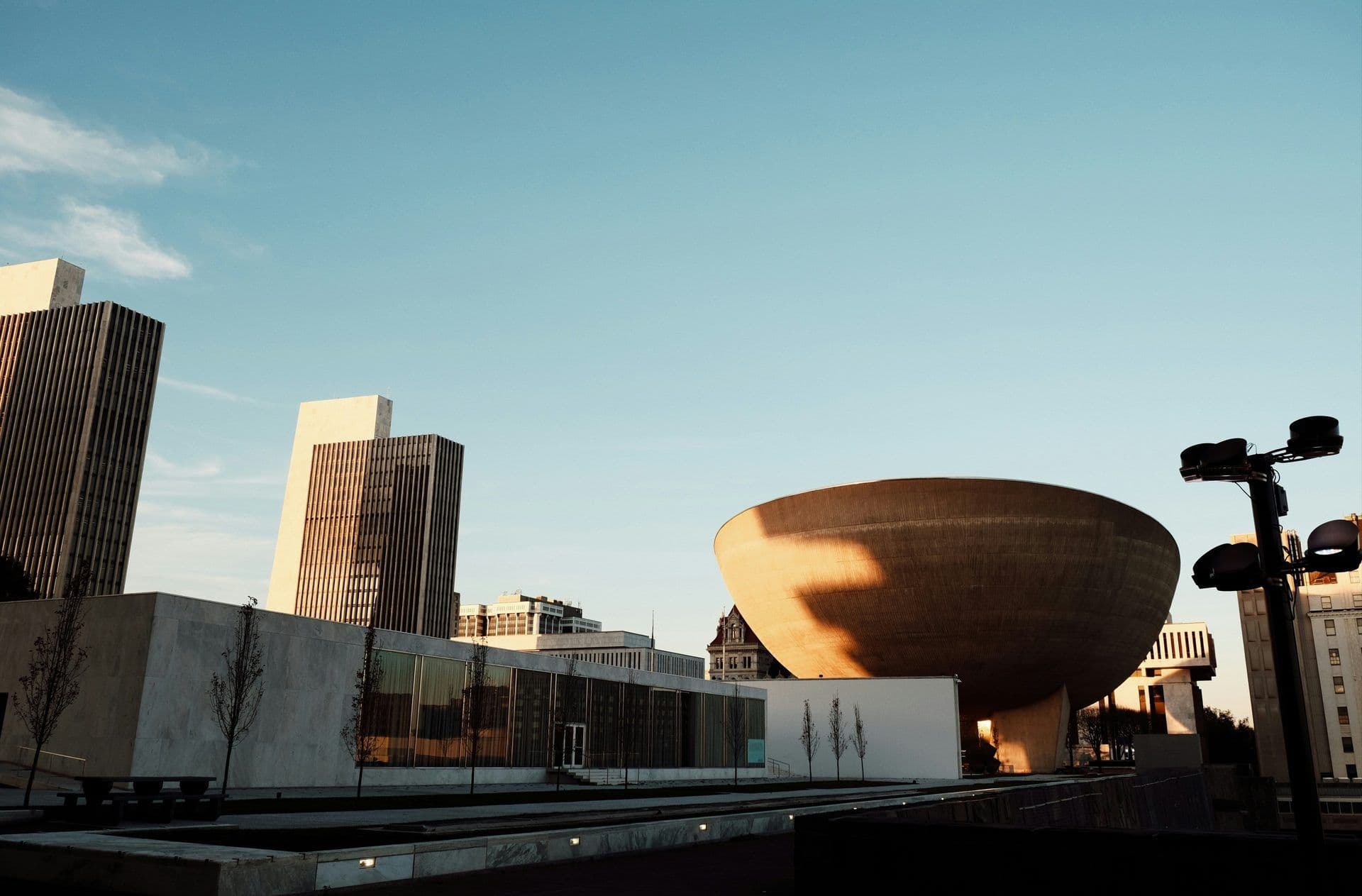 Modern architectural complex featuring a large bowl-shaped auditorium and tall buildings in Albany, New York.
