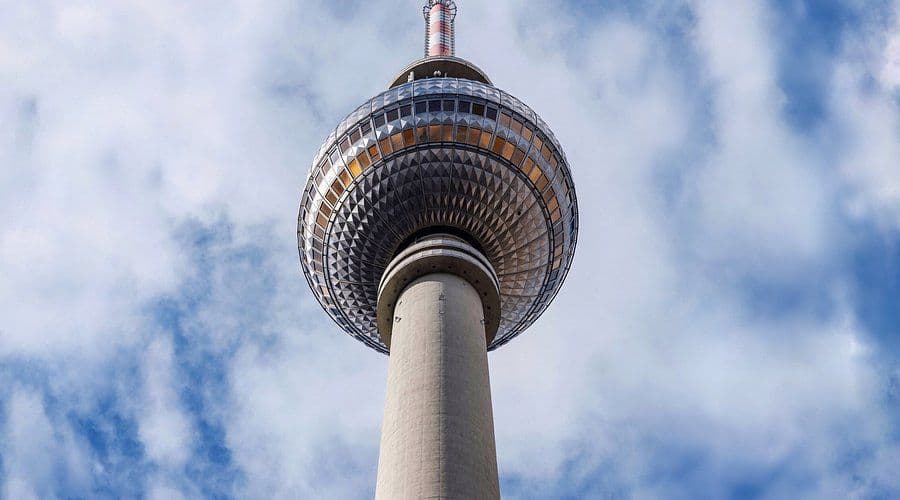 Close-up of the Berlin TV Tower's unique spherical observation deck and antenna against a cloudy sky.