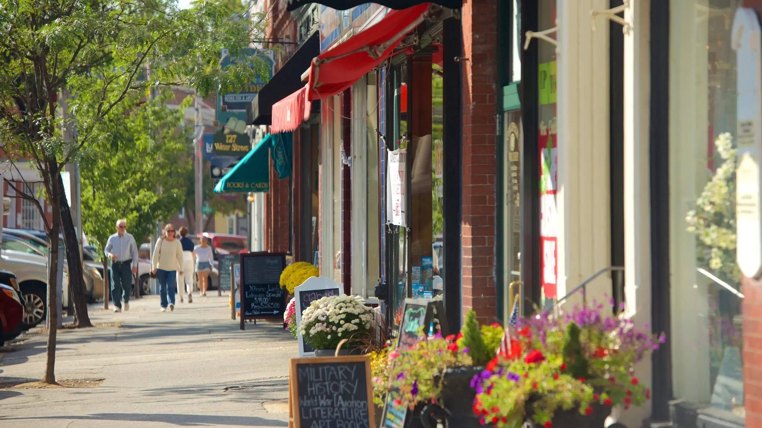 A sunny street in Exeter, New Hampshire, with historic brick storefronts, colorful awnings