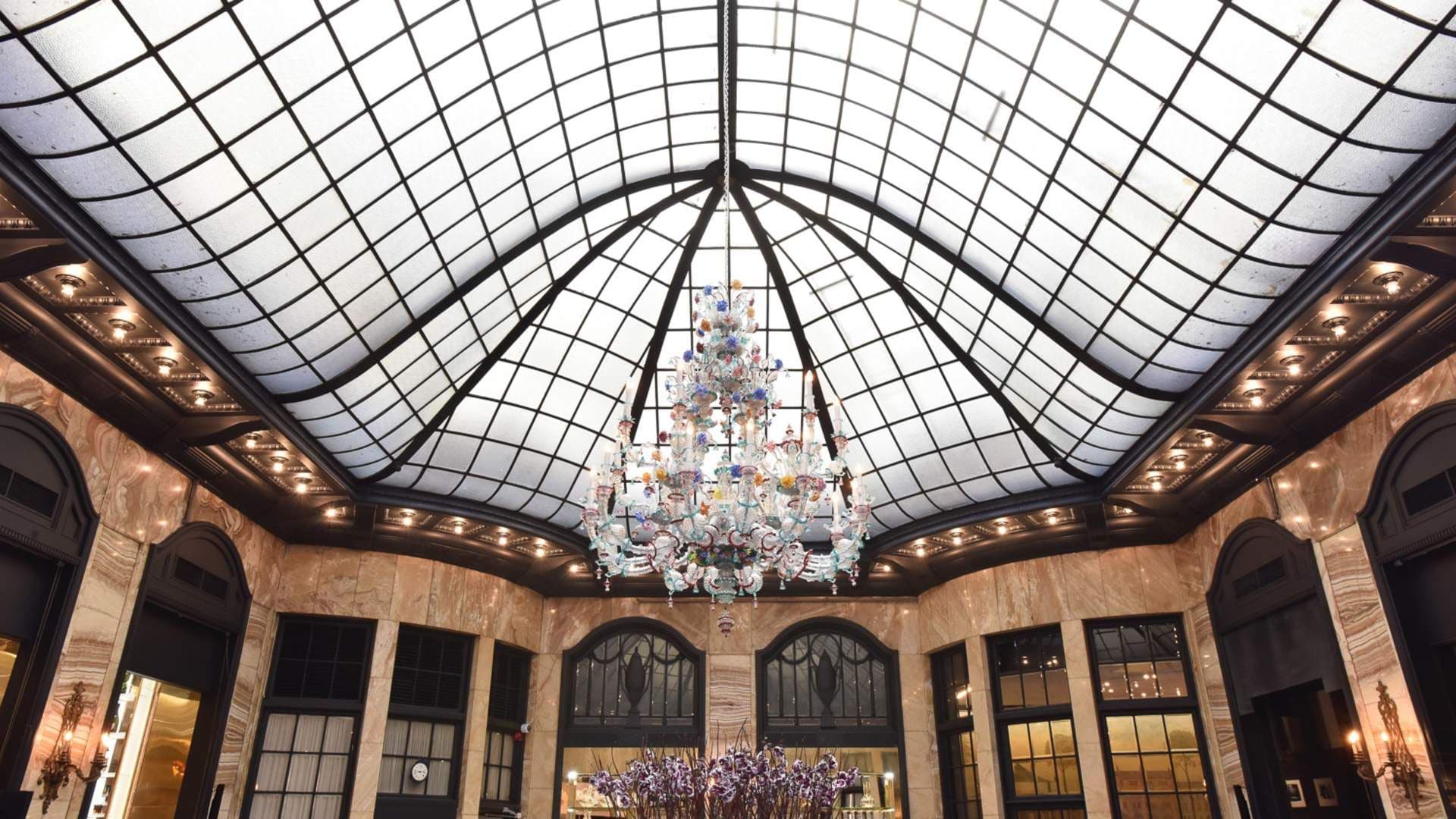 Grand historic event venue with a colorful glass chandelier and a stunning domed skylight.