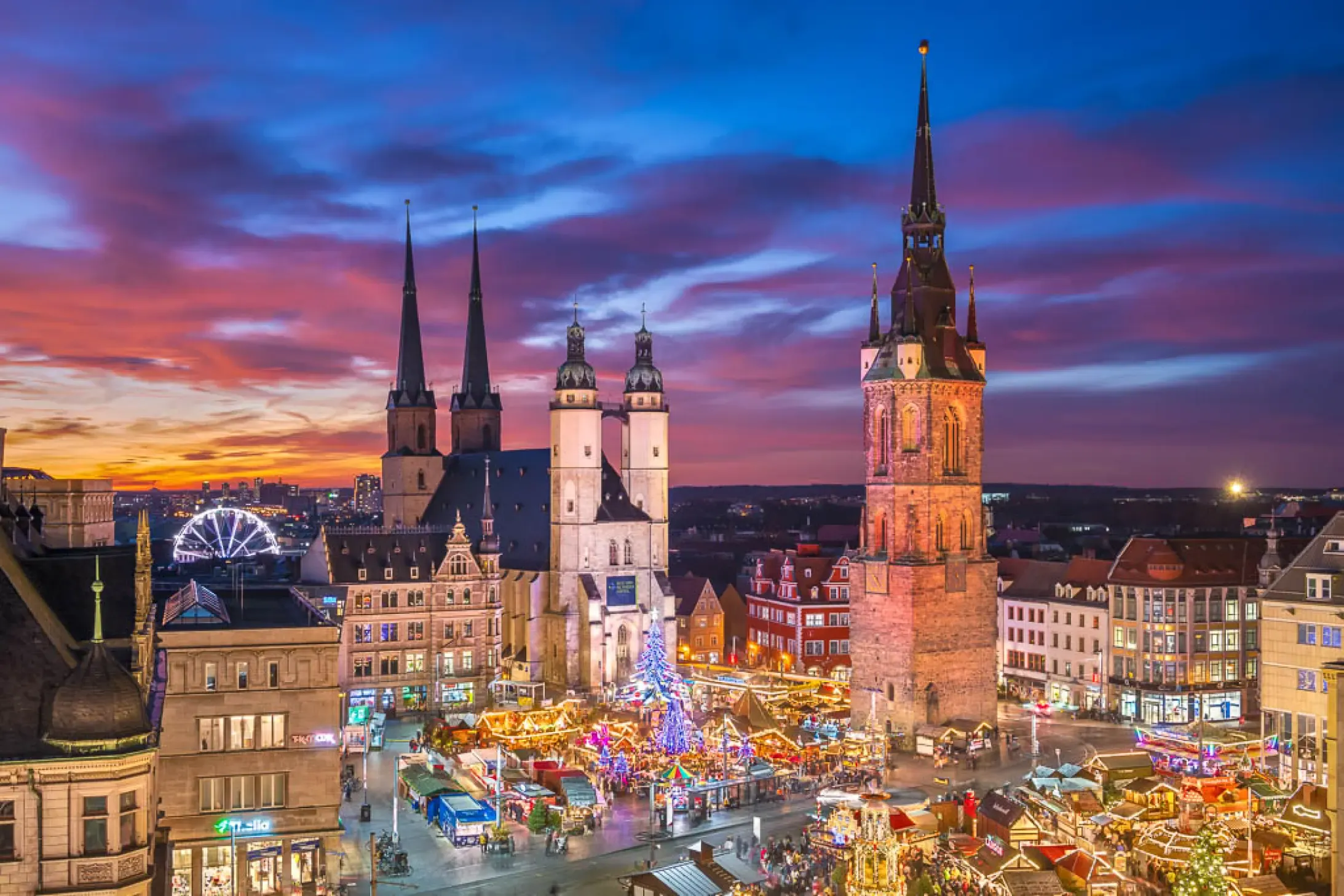 Halle (Saale), Germany, city square at dusk with an illuminated Christmas market and historic architecture.