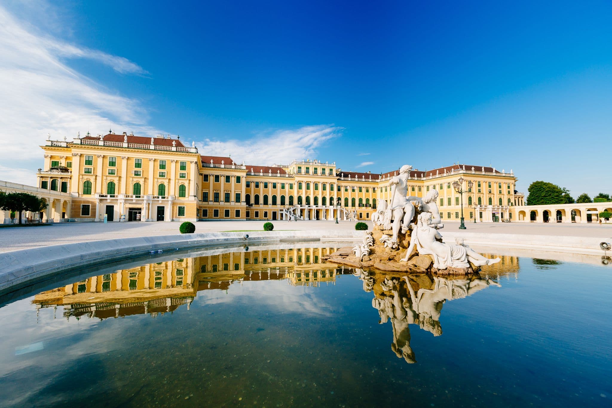 Schönbrunn Palace, a grand historic corporate event venue in Vienna, reflected in a large fountain.