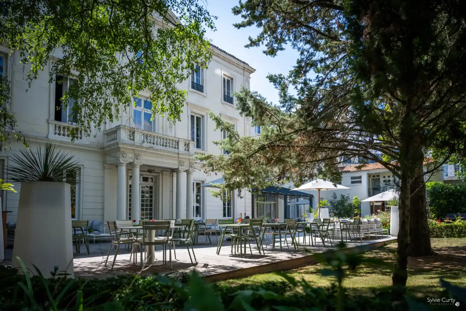Elegant historic venue with a spacious outdoor terrace and seating, surrounded by trees