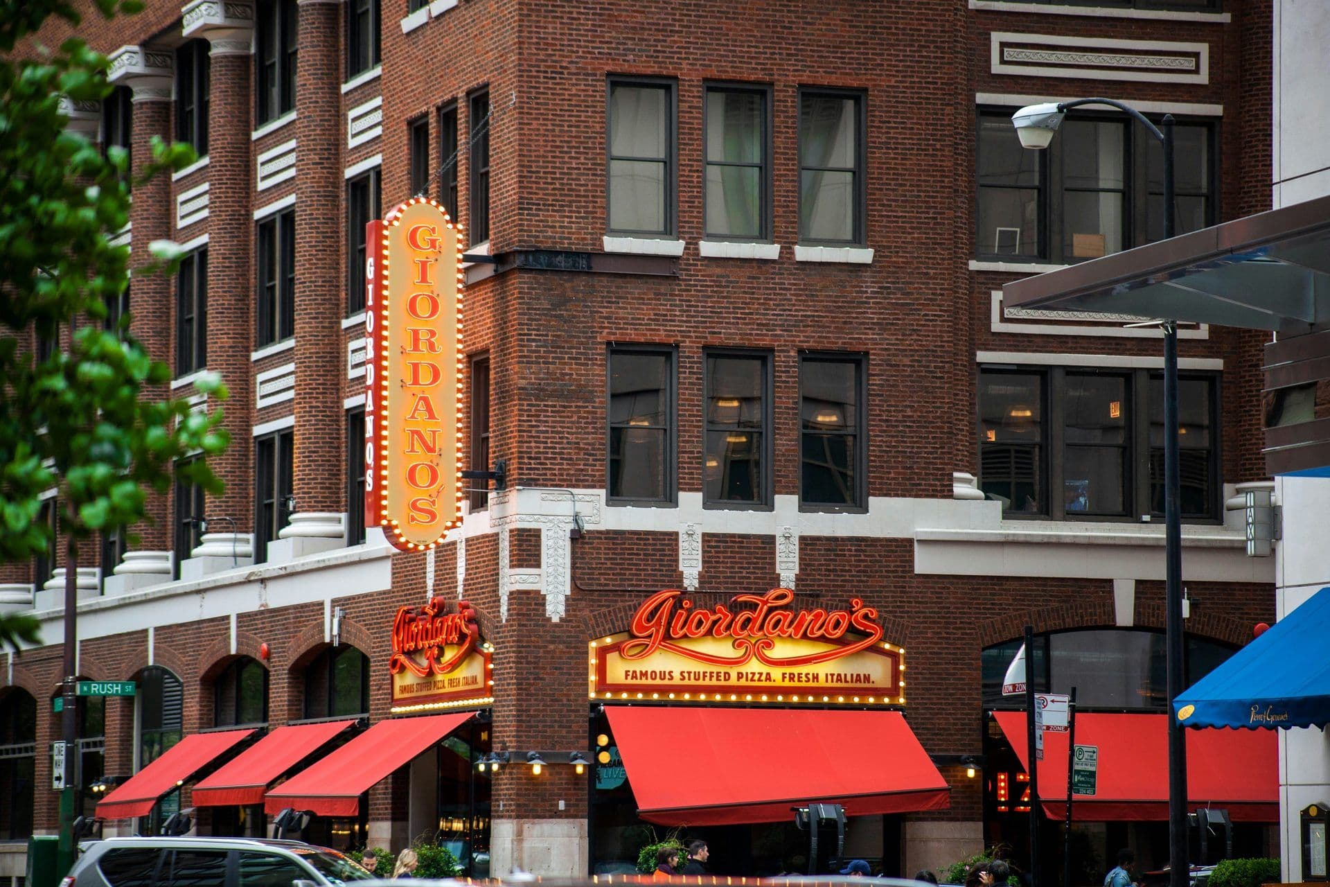 Exterior of Giordano's restaurant on N Rush Street, Chicago, with brick facade and red awnings.