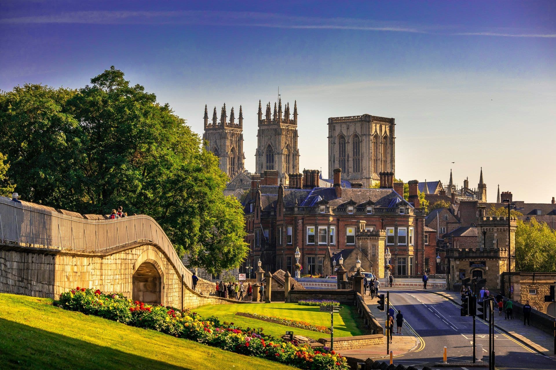 Historic cityscape of York, UK, featuring York Minster, a stone bridge, and vibrant flower beds