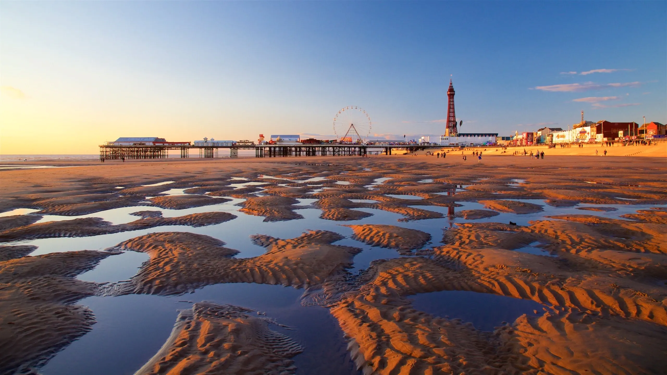 Blackpool beach at sunset with a pier, Ferris wheel, and iconic tower, ideal for a corporate offsite.