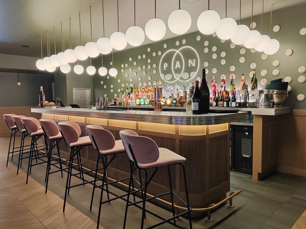 Mini-bar moderne d'hôtel avec bouteilles, verres et snacks élégamment organisés