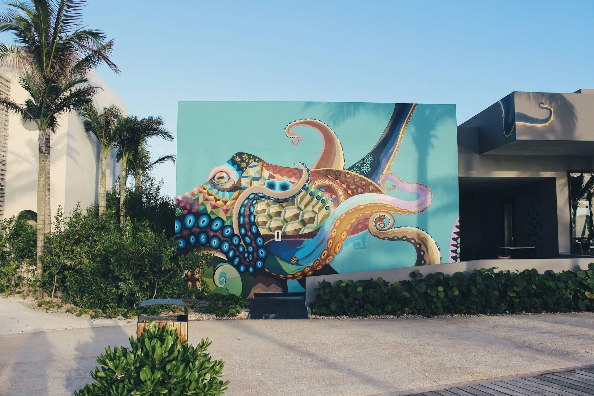 Vibrant octopus mural on a modern building, a unique corporate event venue with tropical landscaping.