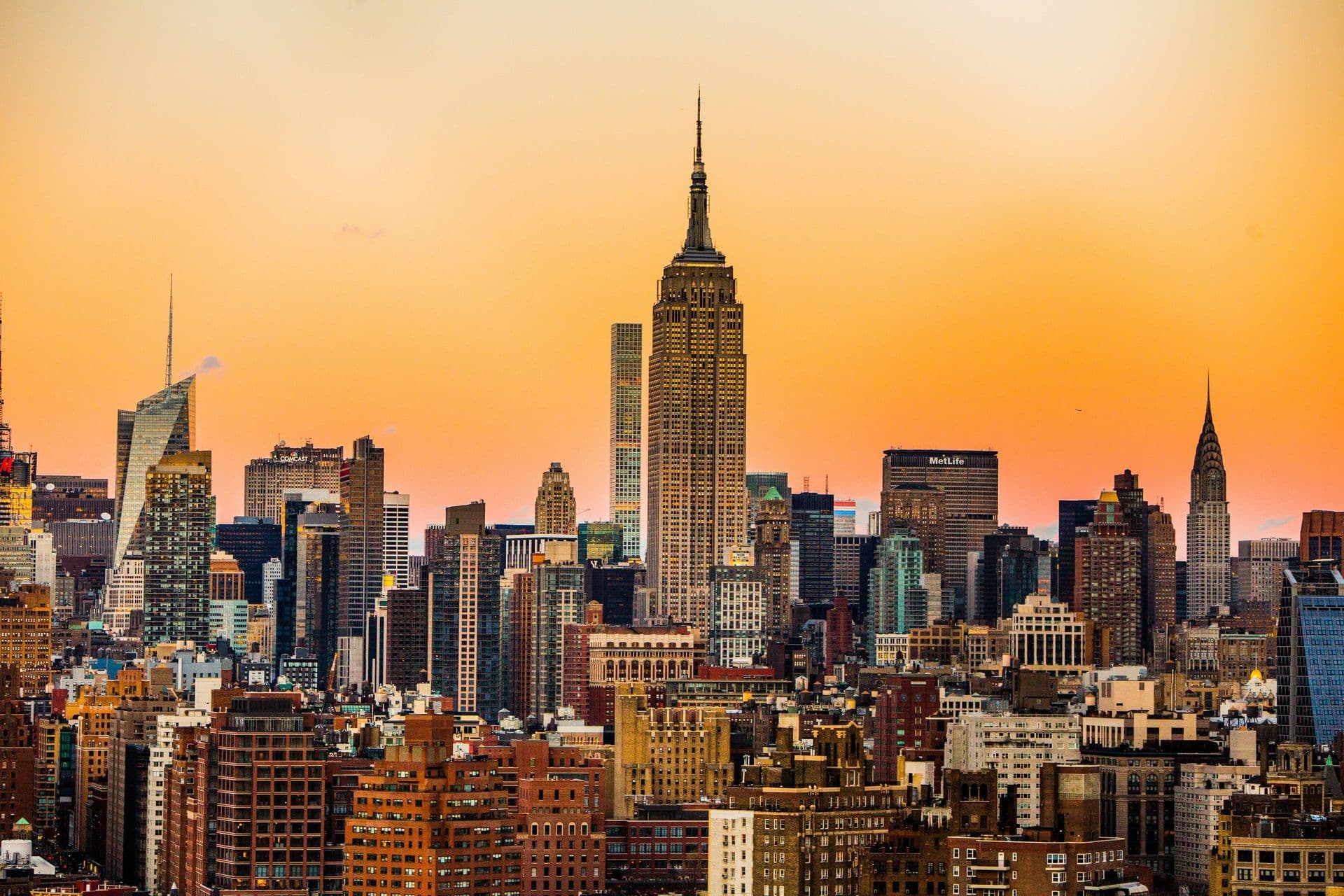 The iconic New York City skyline at sunset, featuring the Empire State Building and Chrysler Building.