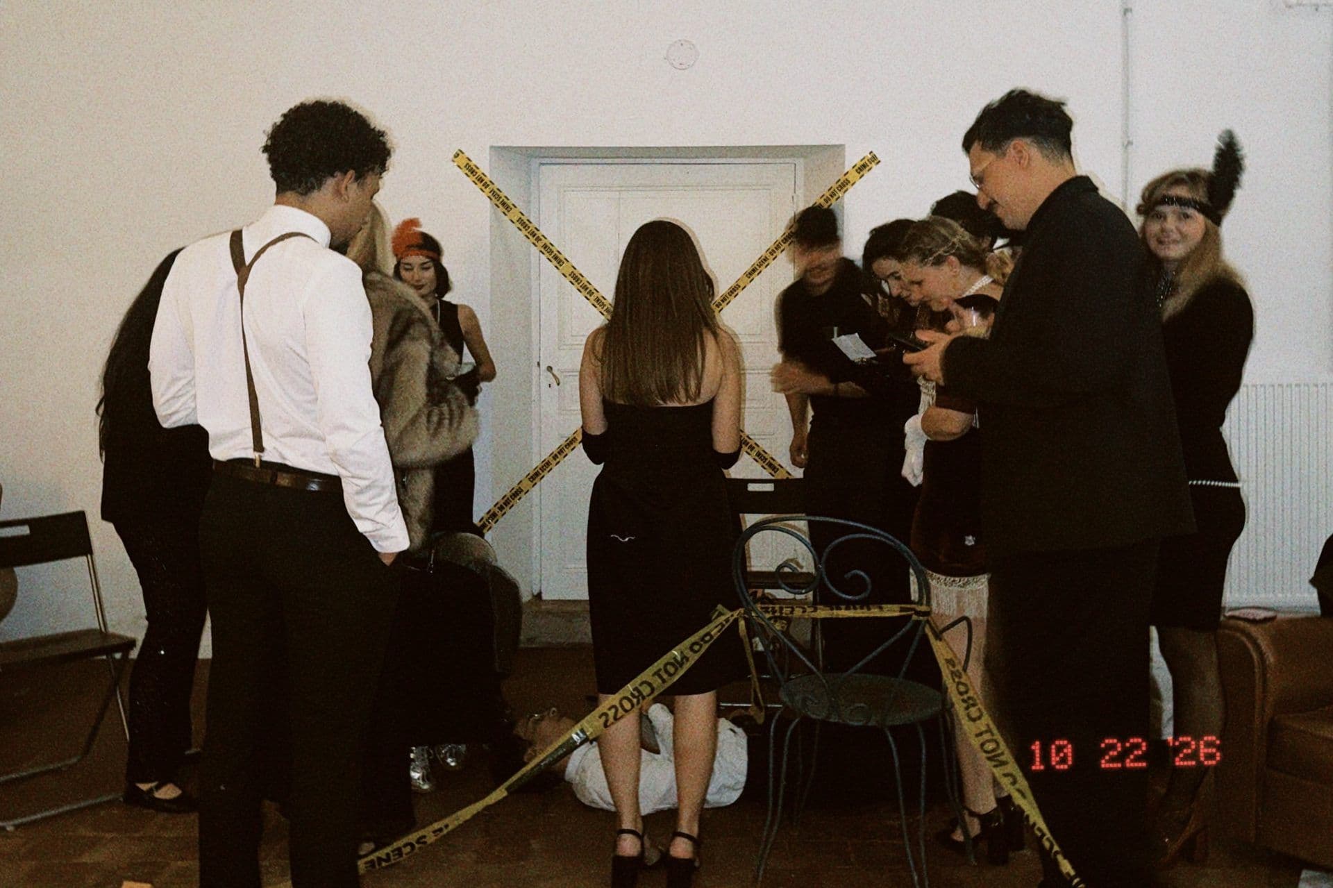 Colleagues in 1920s costume gather around a taped-off crime scene during a murder mystery team building evening at Le Grand S