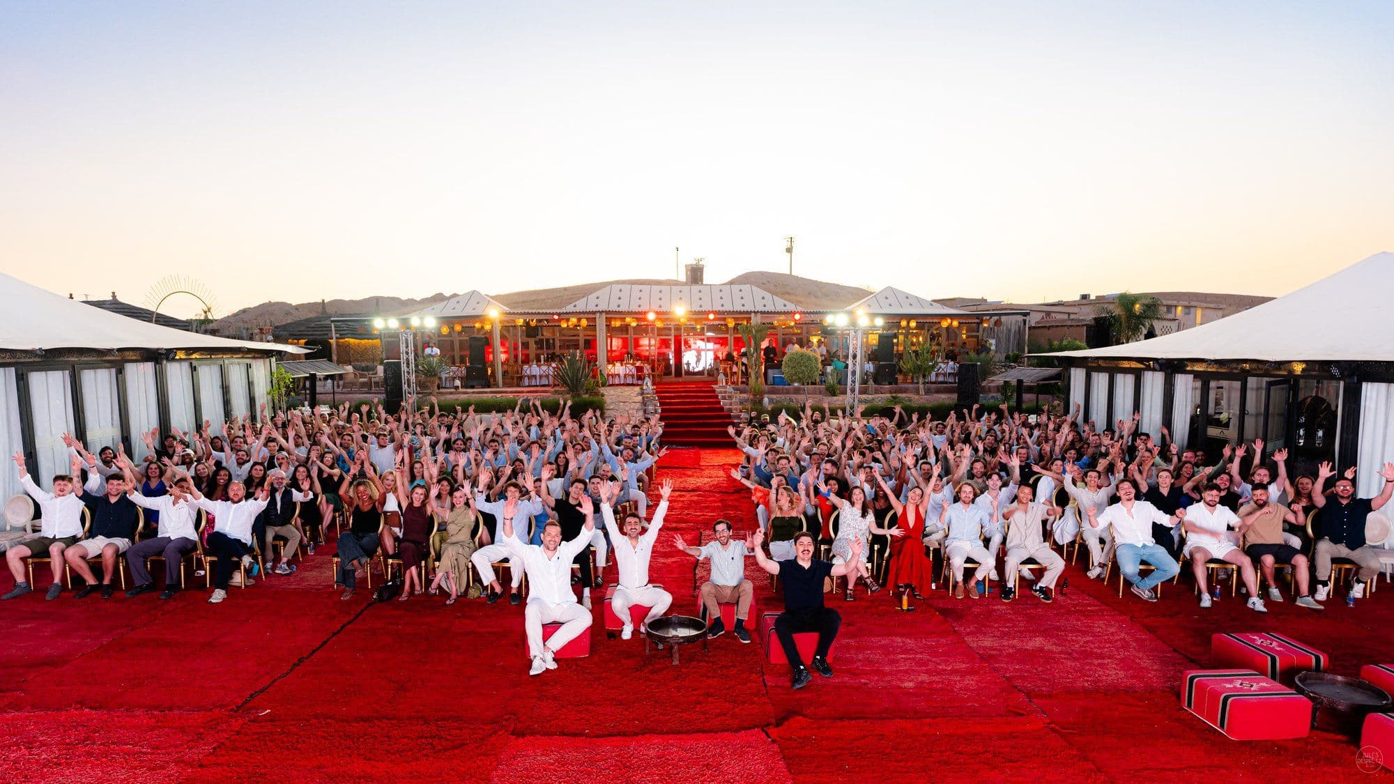 The Naboo team cheering at a desert camp in the Agafay desert at sunset during the Naboo global offsite near Marrakech, May 2026