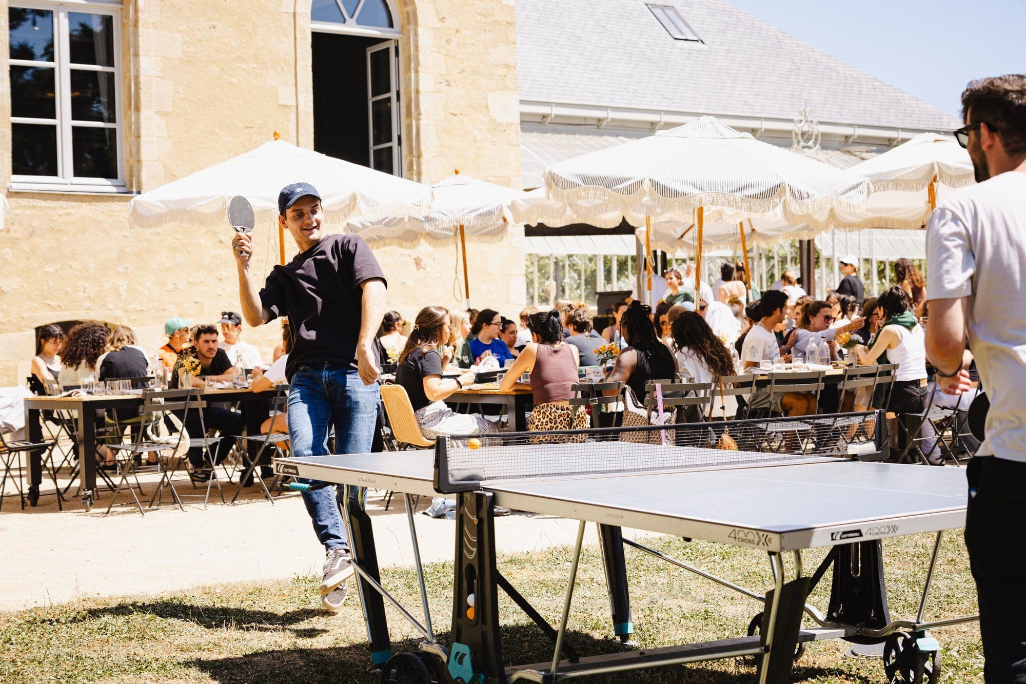 Naboo team at an outdoor lunch under umbrellas with a ping-pong table on the lawn, Naboo team seminar, July 2025