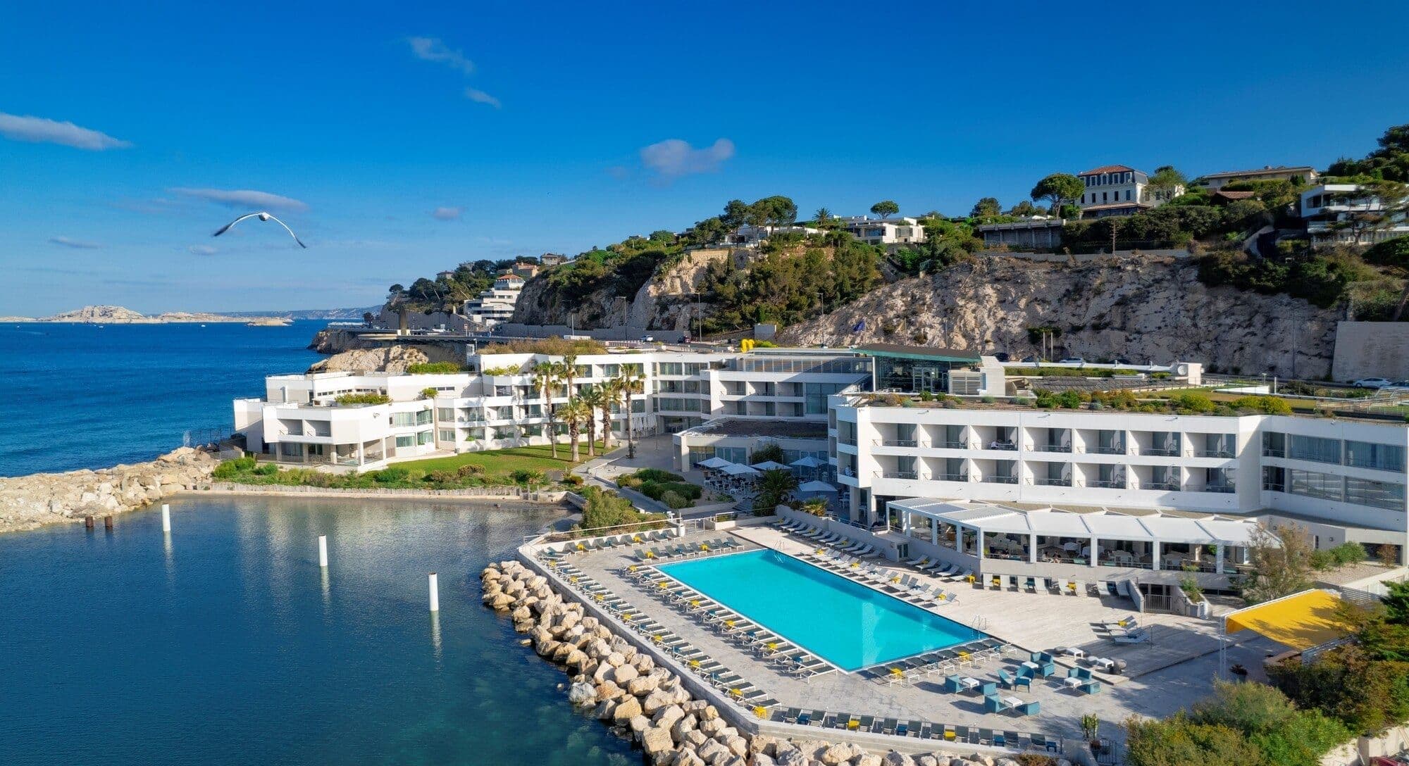 Aerial view of a modern waterfront hotel in Marseille, an ideal corporate event venue with a large pool.