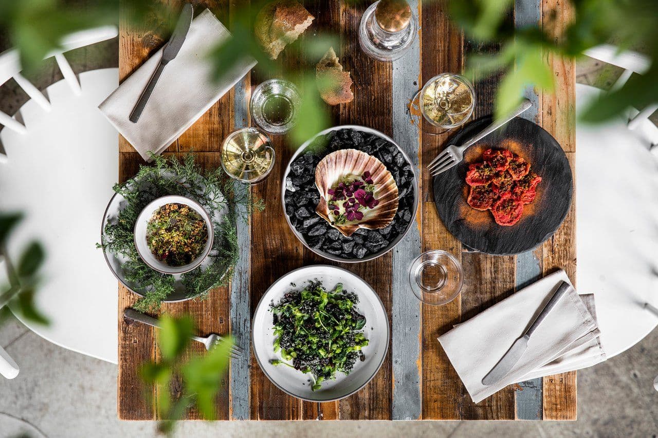 Gourmet corporate dinner setting with scallops, salads, and wine on a rustic wooden table.