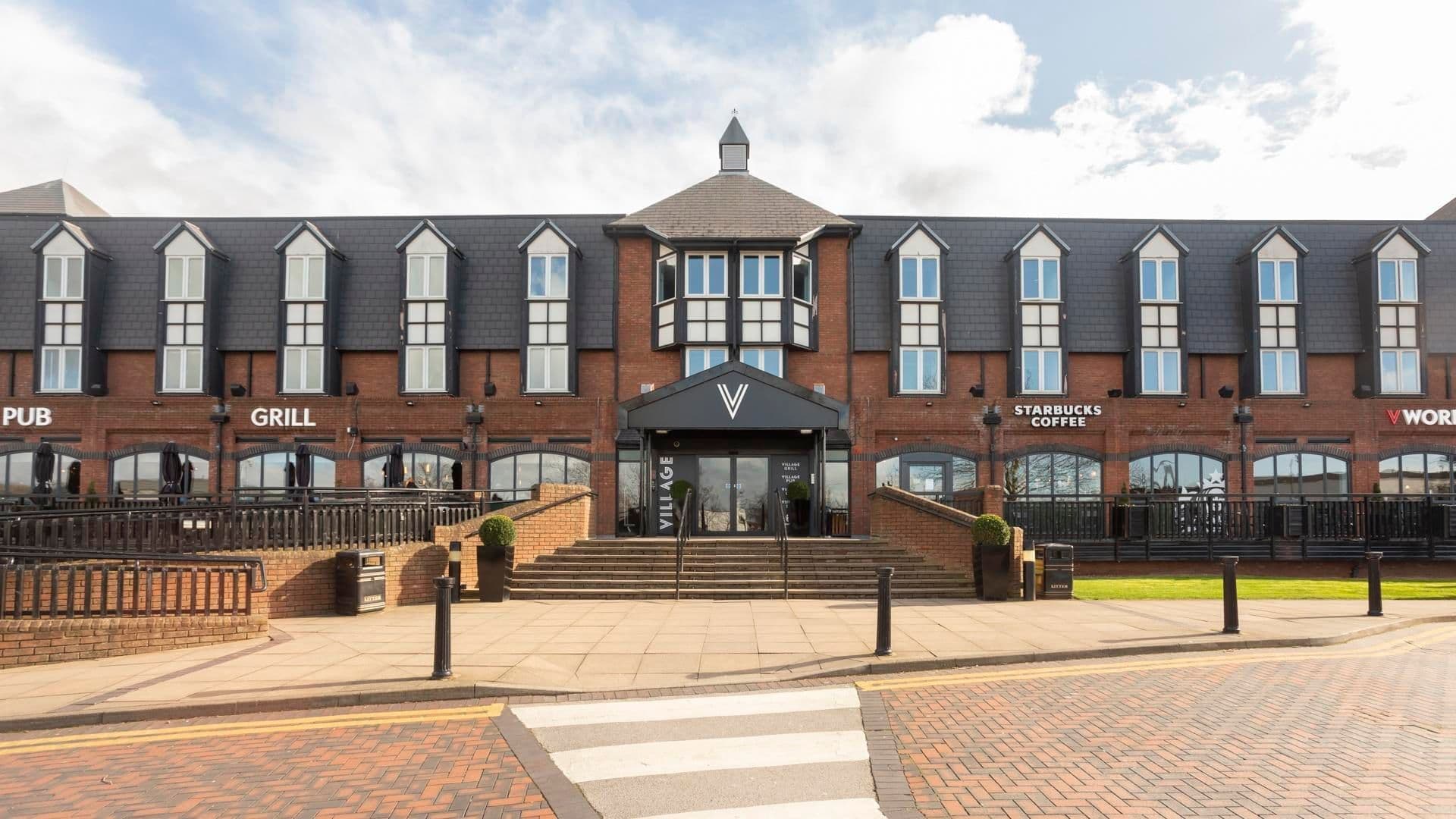 Exterior of the Village Hotel Nottingham, a brick corporate event venue with a grill and Starbucks.