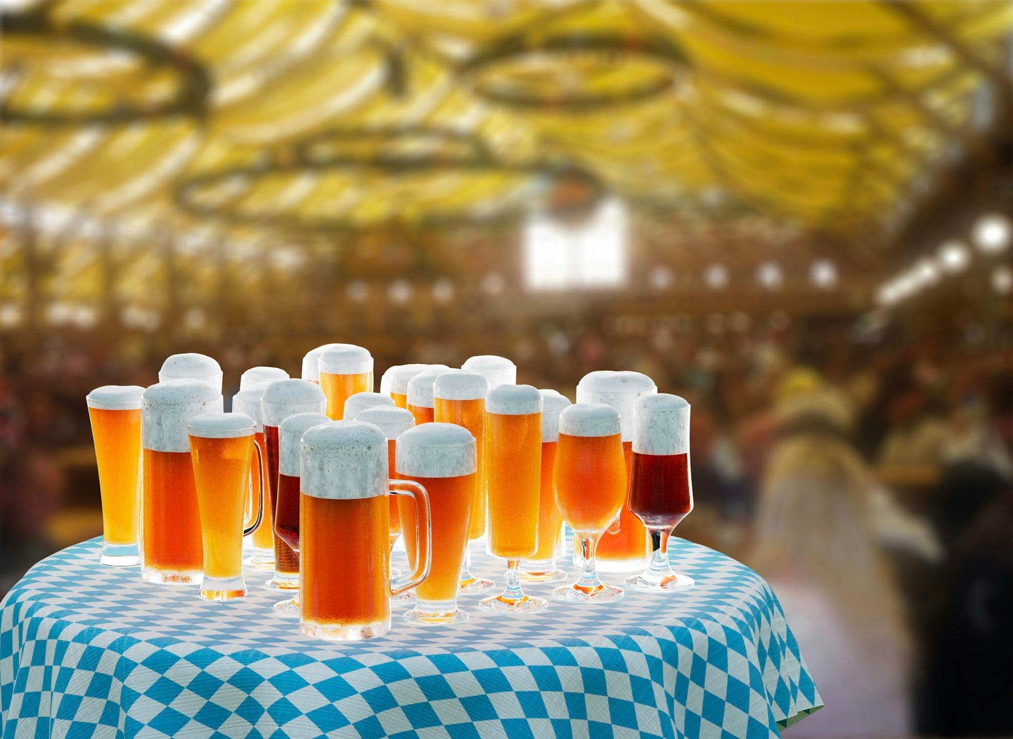 Rows of frothy beer glasses on a checkered Oktoberfest table