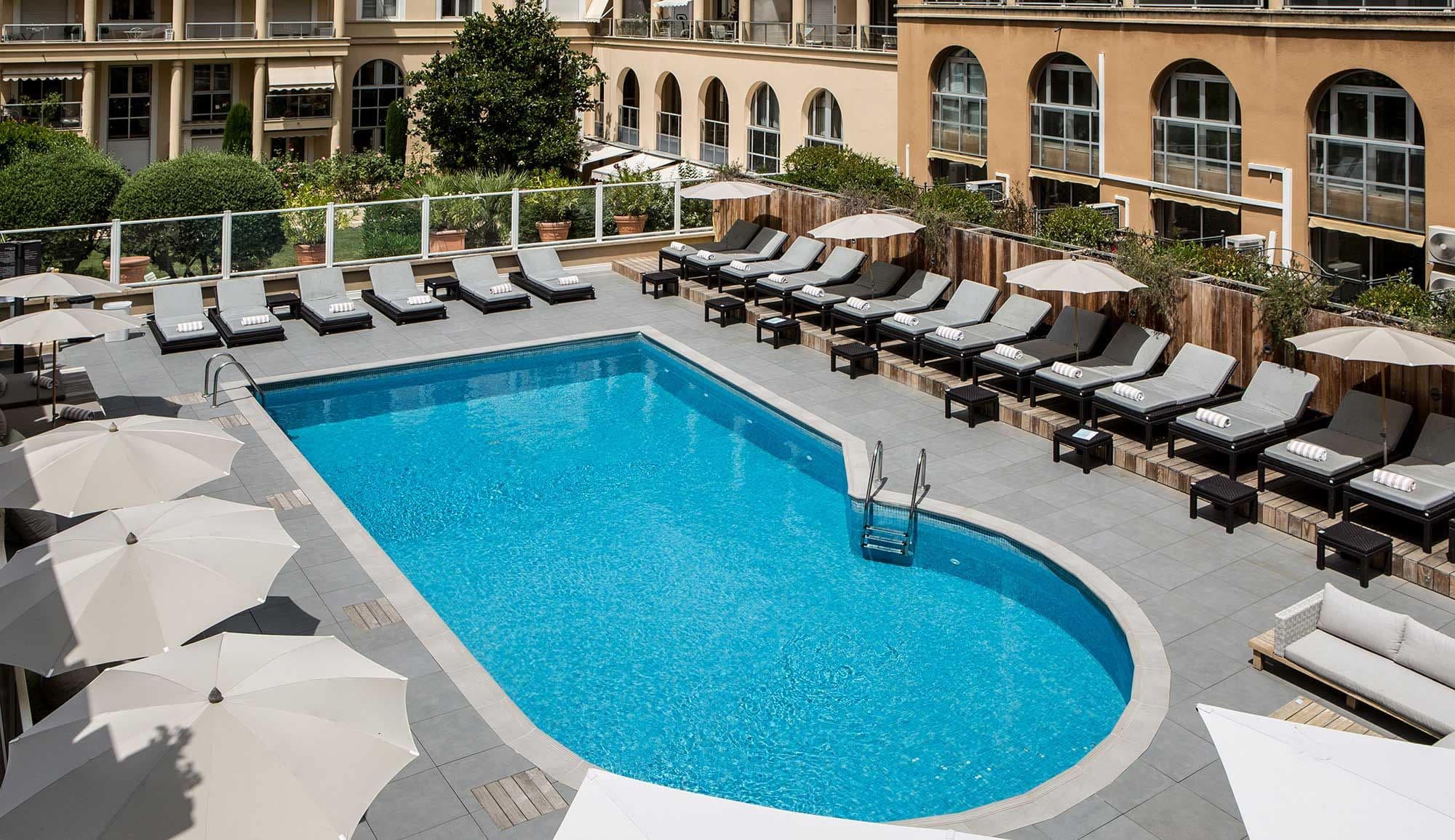 An inviting outdoor swimming pool area with sun loungers and umbrellas at a corporate event venue.