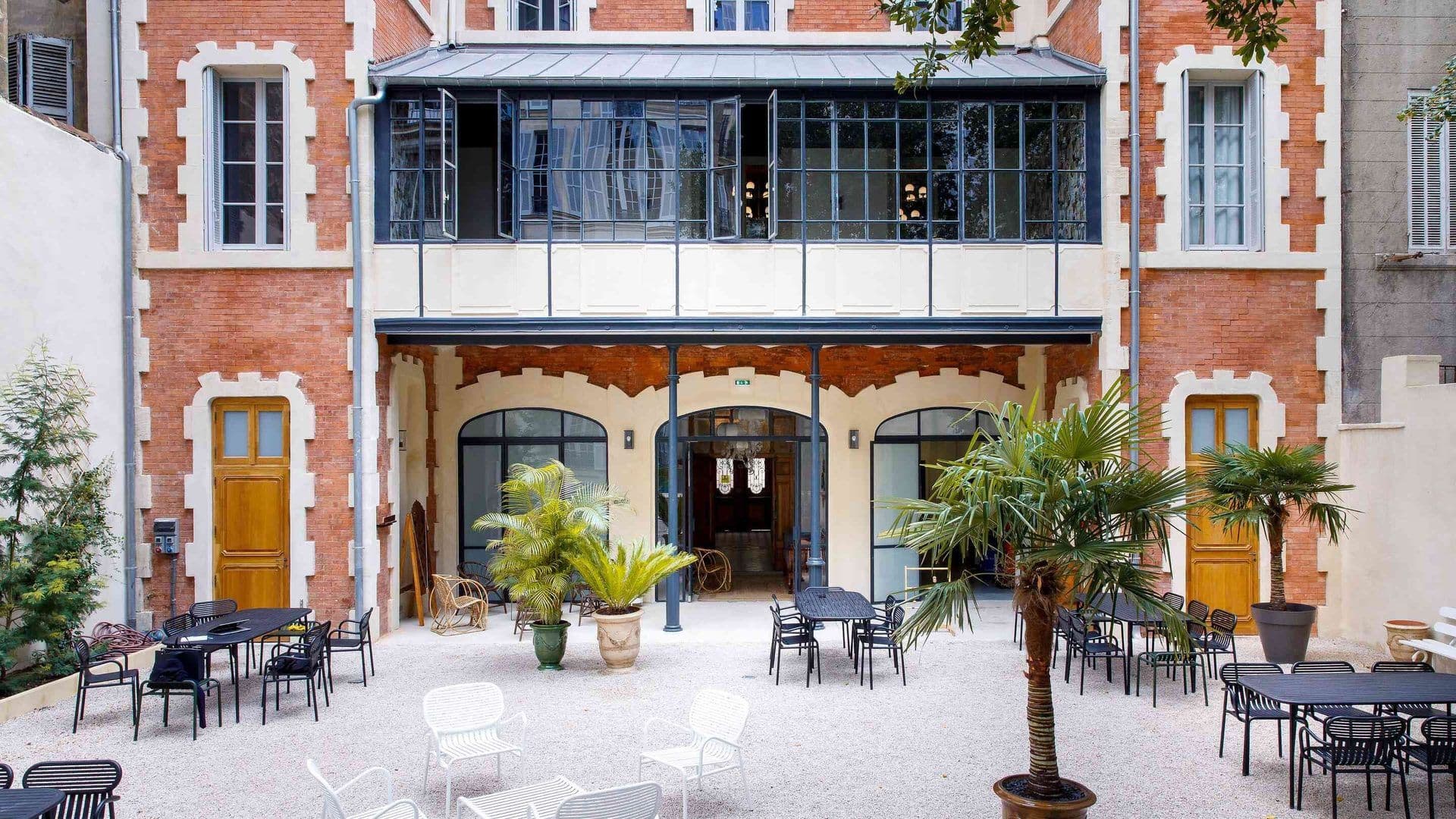An inviting outdoor event space with modern tables and chairs, surrounded by a historic brick building.