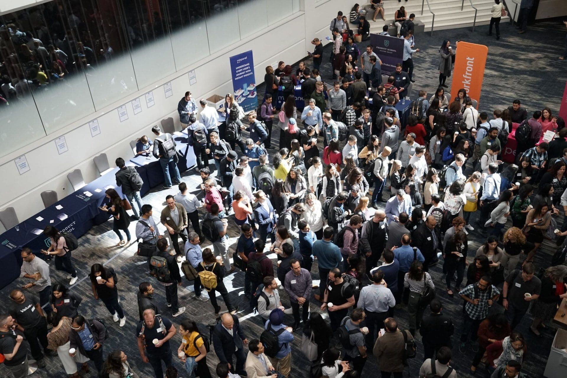 Large group of professionals networking at a MICE event in a spacious corporate event venue.