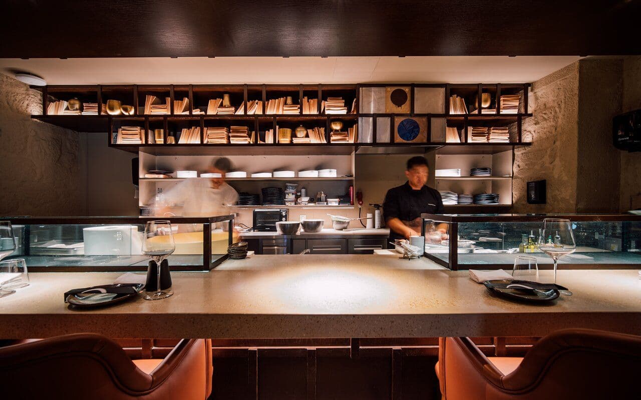 A modern sushi bar with chefs behind a counter, set for a private dining experience or business meal.