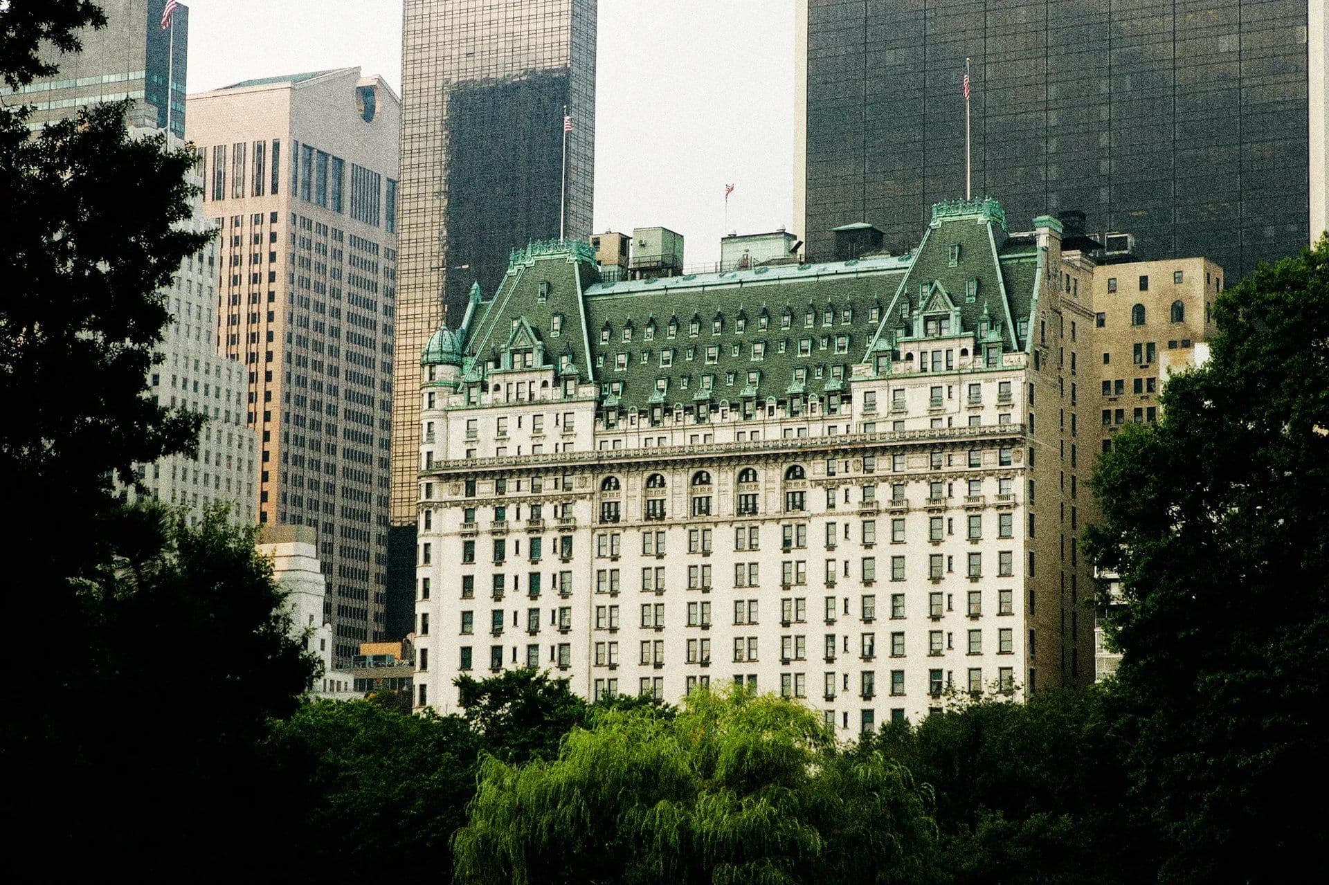 The iconic Plaza Hotel in New York City, a historic corporate event venue, seen through lush green trees.