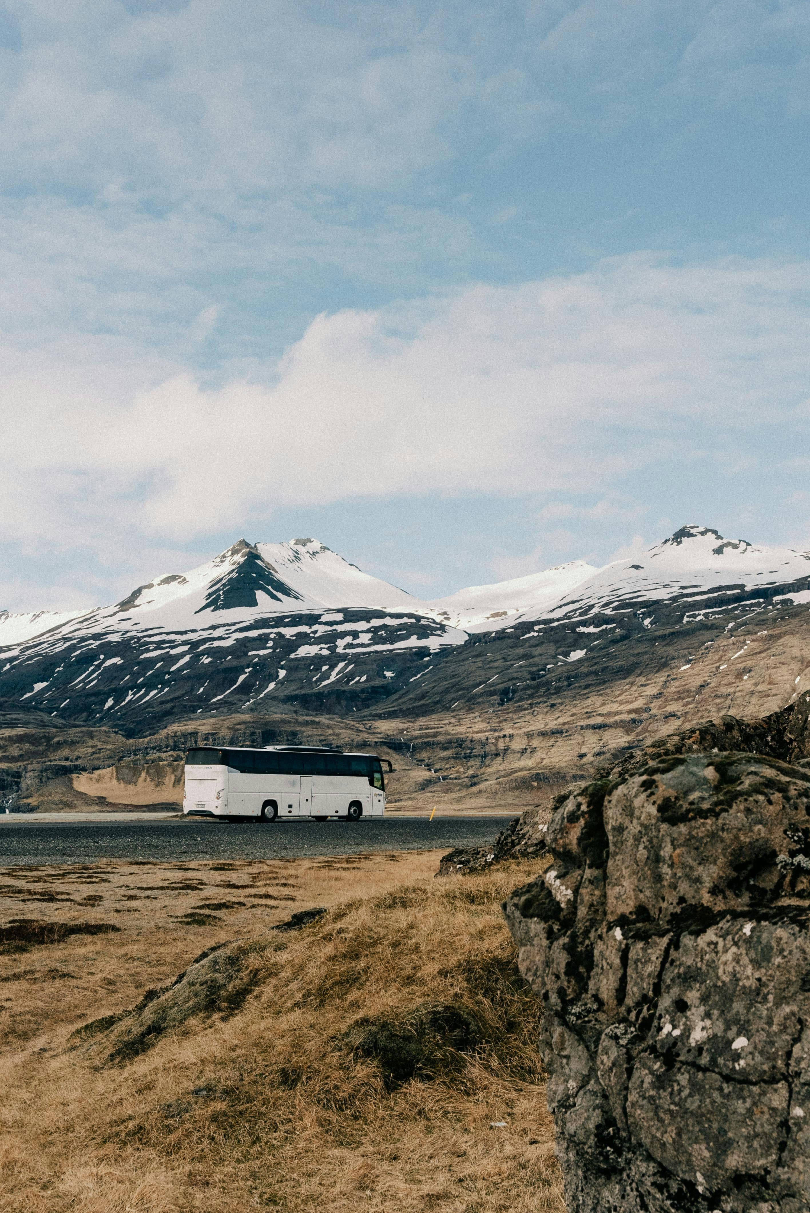 White coach bus parked before snow-capped mountains