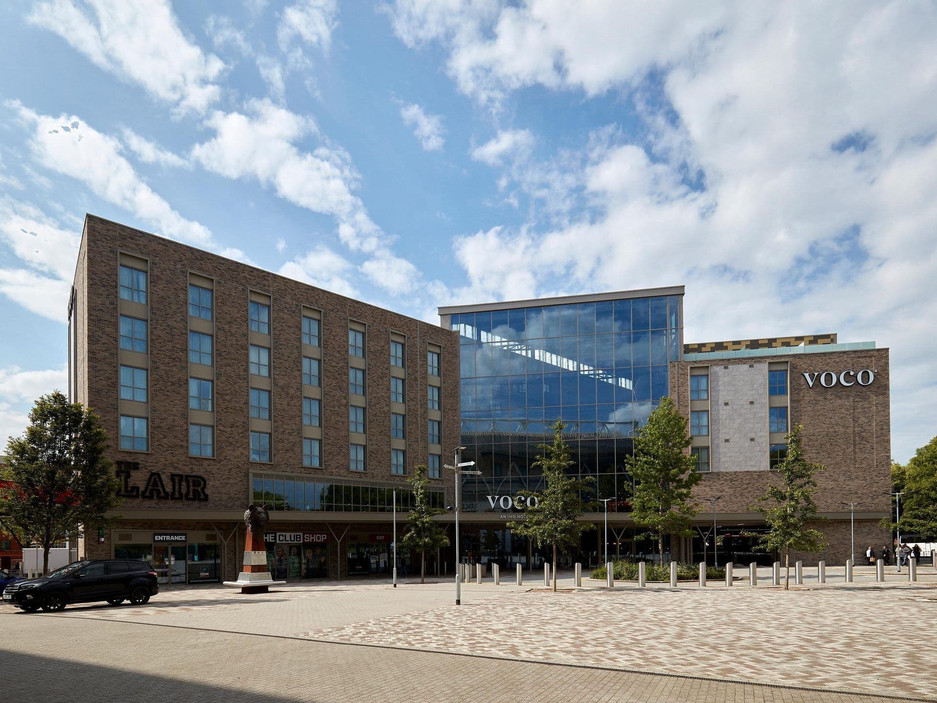 Exterior view of the modern Voco Leicester hotel, a corporate event venue with brick and glass architecture.